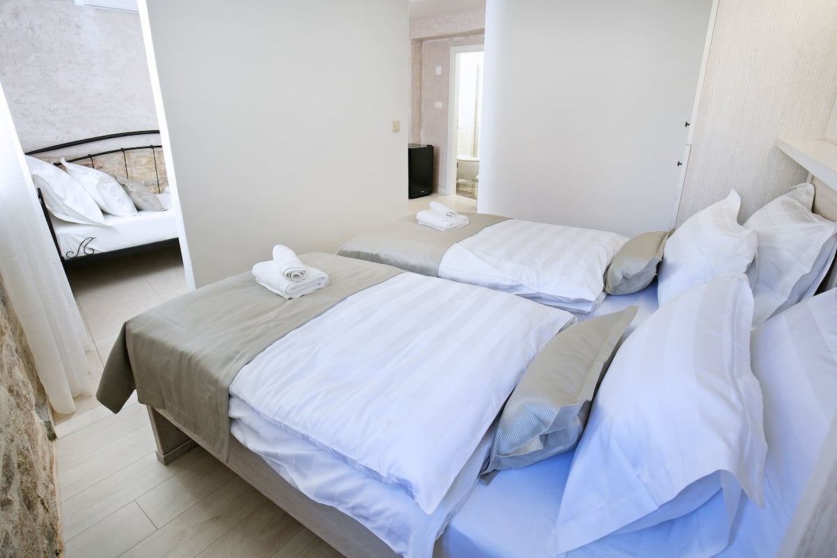 A hotel room with two beds, a bathroom, and a TV.