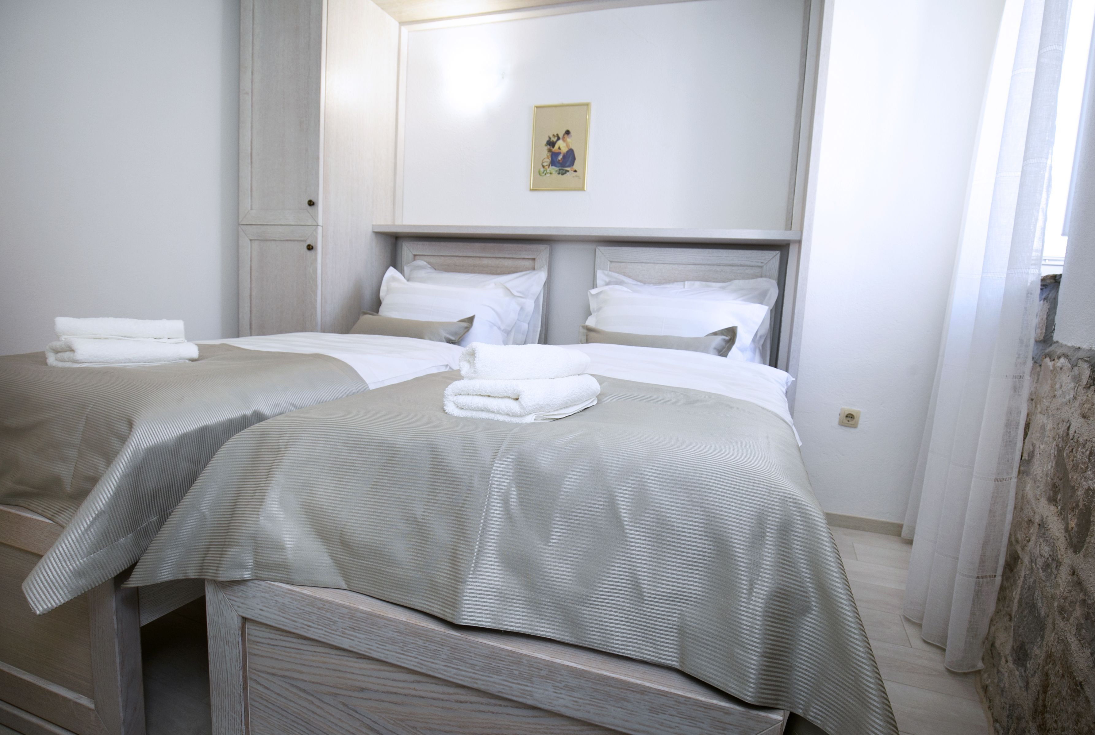 A hotel room with two beds, each with neatly folded white towels.