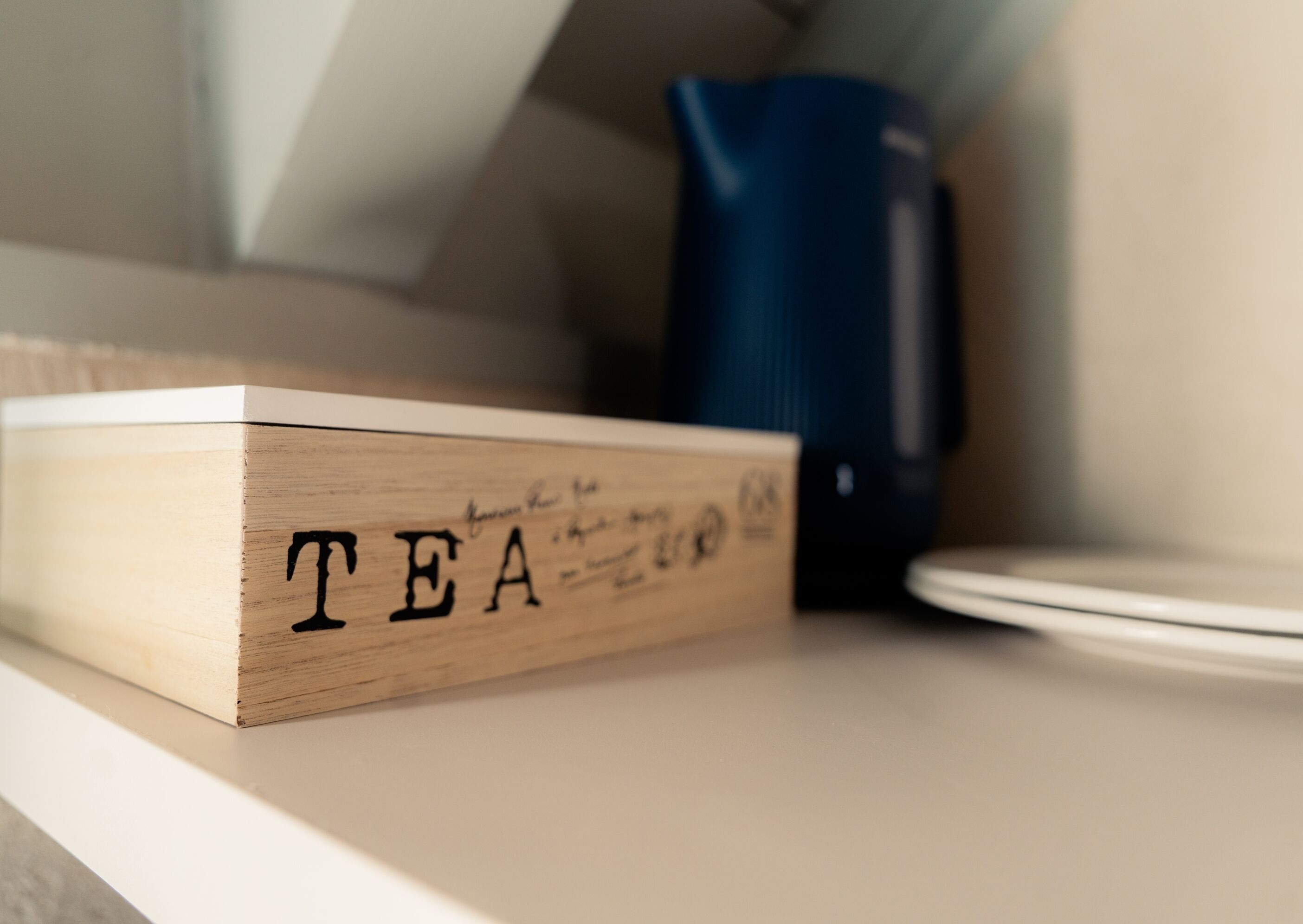 A wooden box with the word 'TEA' on a shelf.