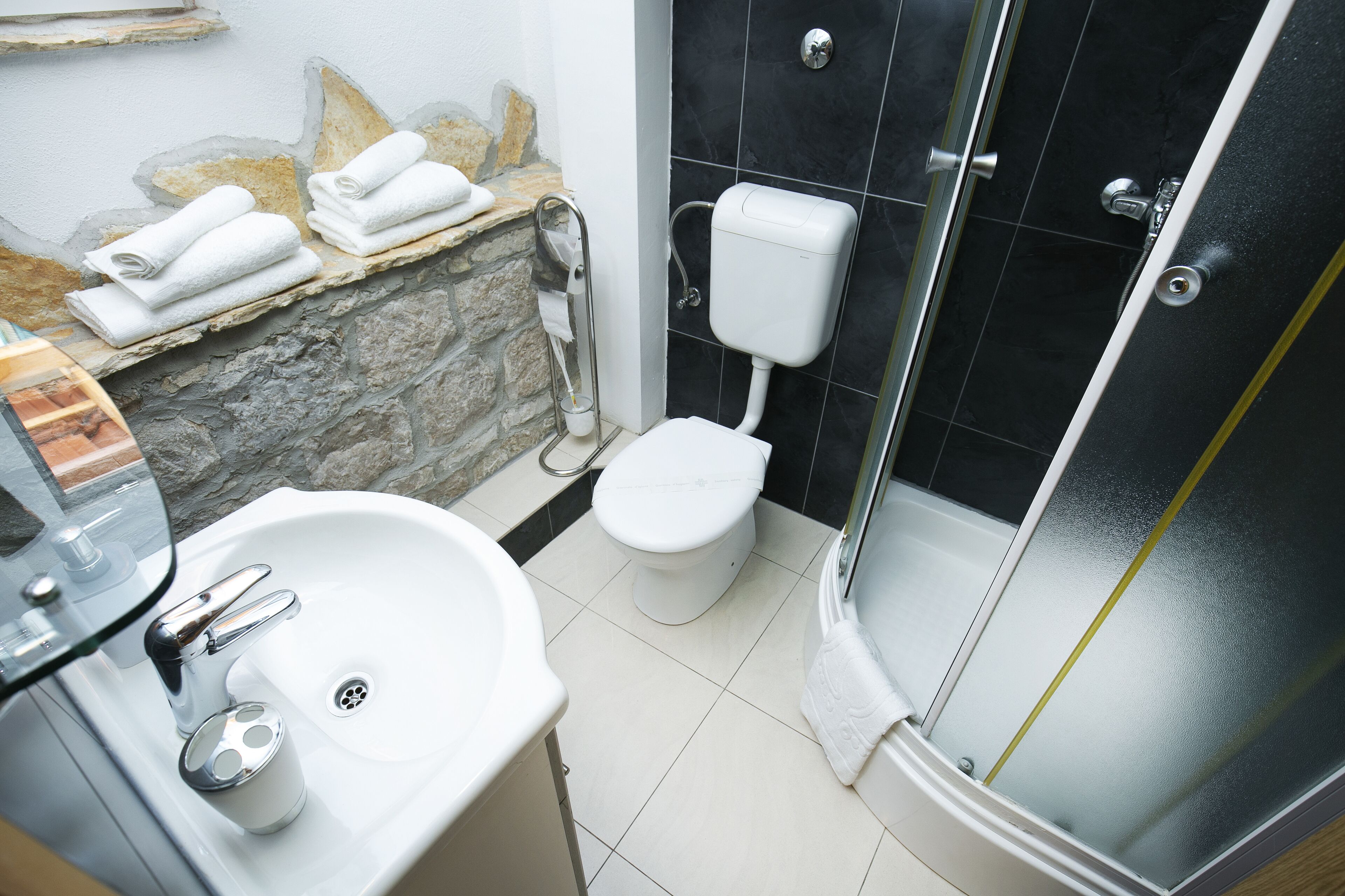 Ein Badezimmer mit einem weißen Waschbecken, einer Toilette und einer Duschkabine aus Glas.