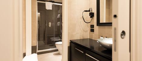 A modern bathroom with a glass shower enclosure, a black vanity with a large sink, and a mirror above the sink.