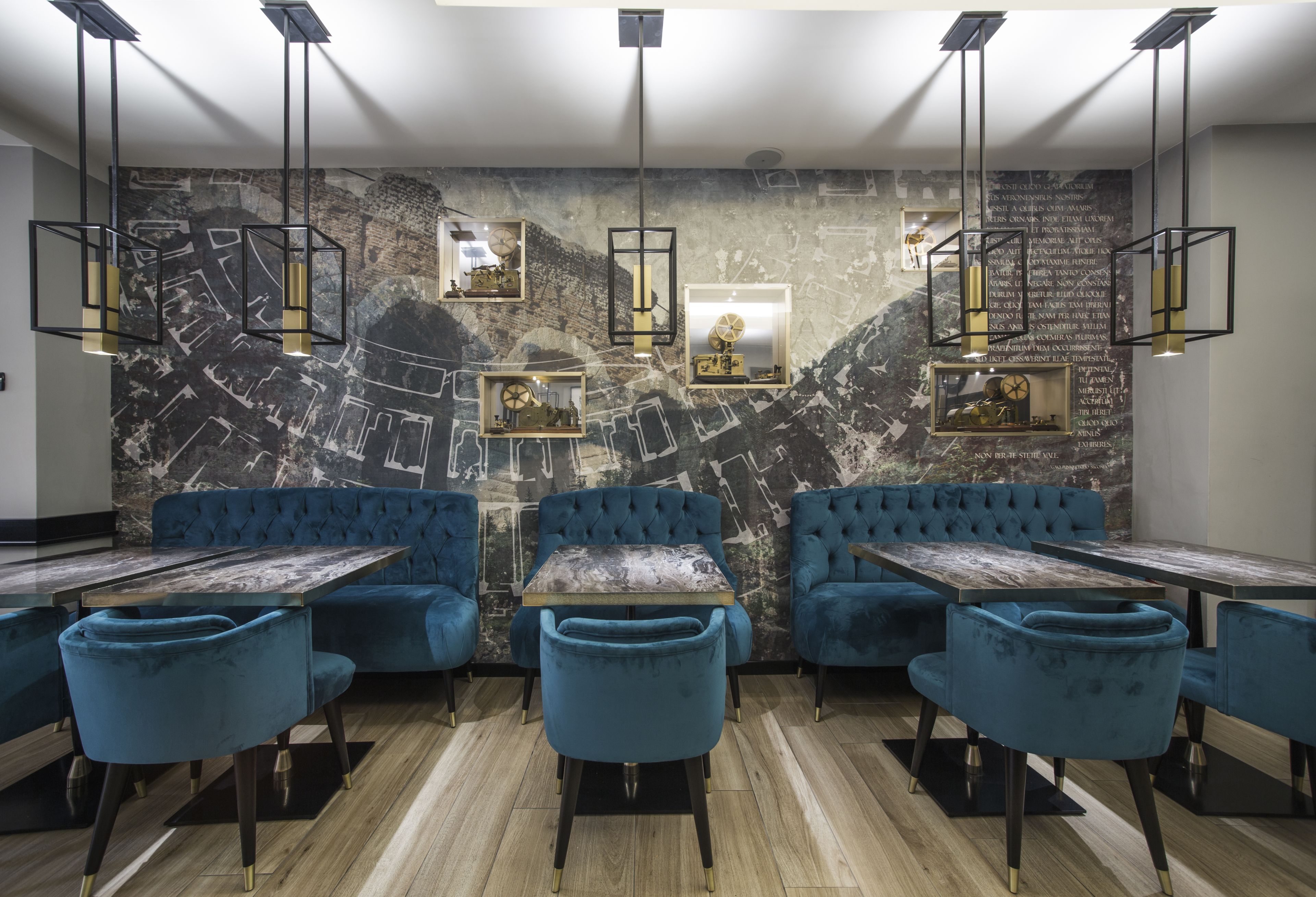Un interior de restaurante moderno con asientos de terciopelo azul, mesas de madera e iluminación colgante.