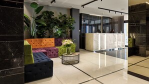 A modern lobby with a marble reception desk, plush seating areas, and large green plants. - Hotel Milano & Spa (Verona)