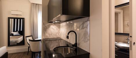 A modern hotel room with a separate dining area, a large mirror, and a marble backsplash.