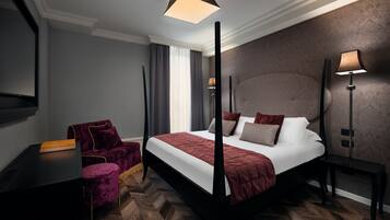 Una camera d'albergo moderna con un ampio letto, una scrivania, una sedia e un comodino.