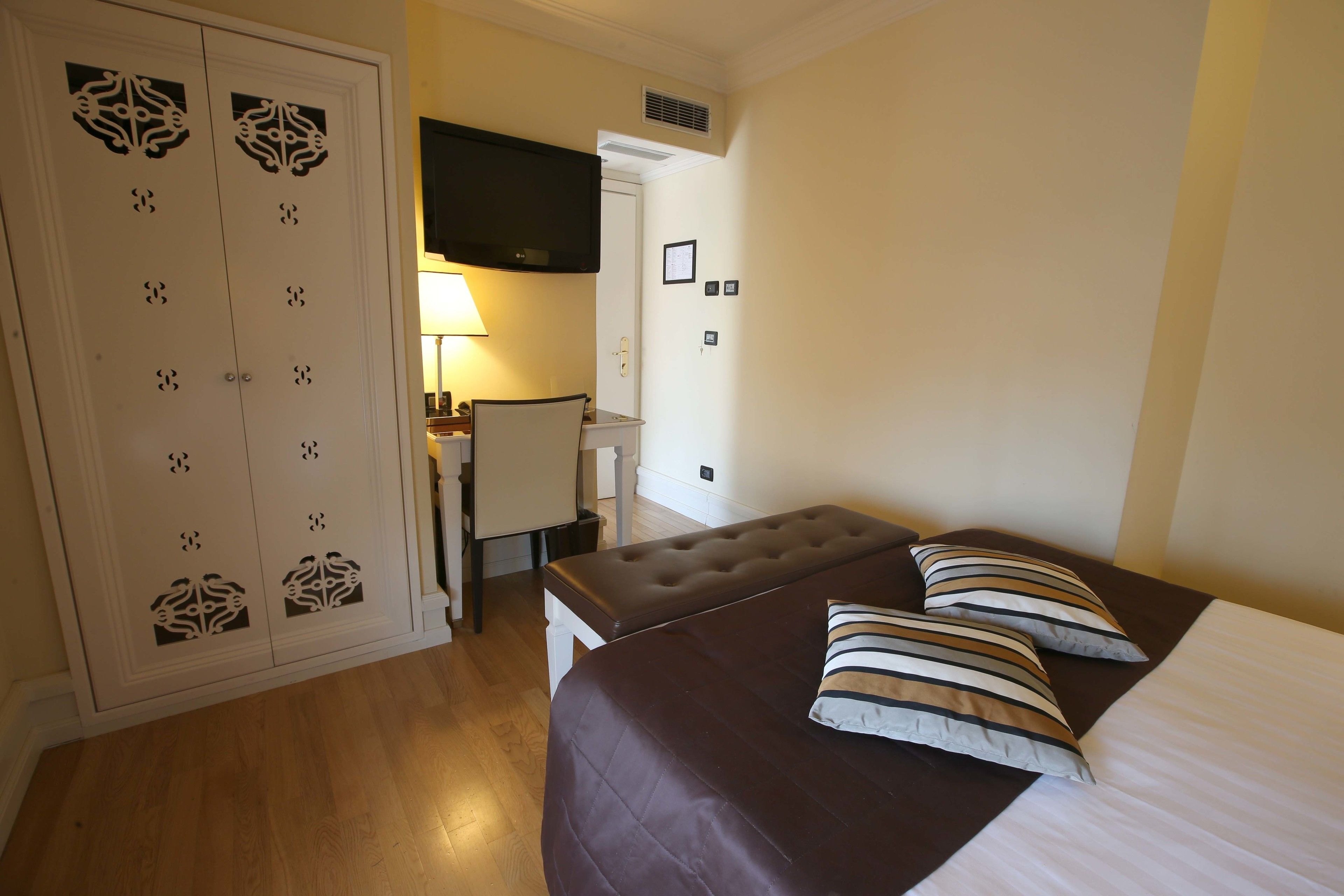 Un dormitorio con cama, dos almohadas, un escritorio, una silla y un armario.