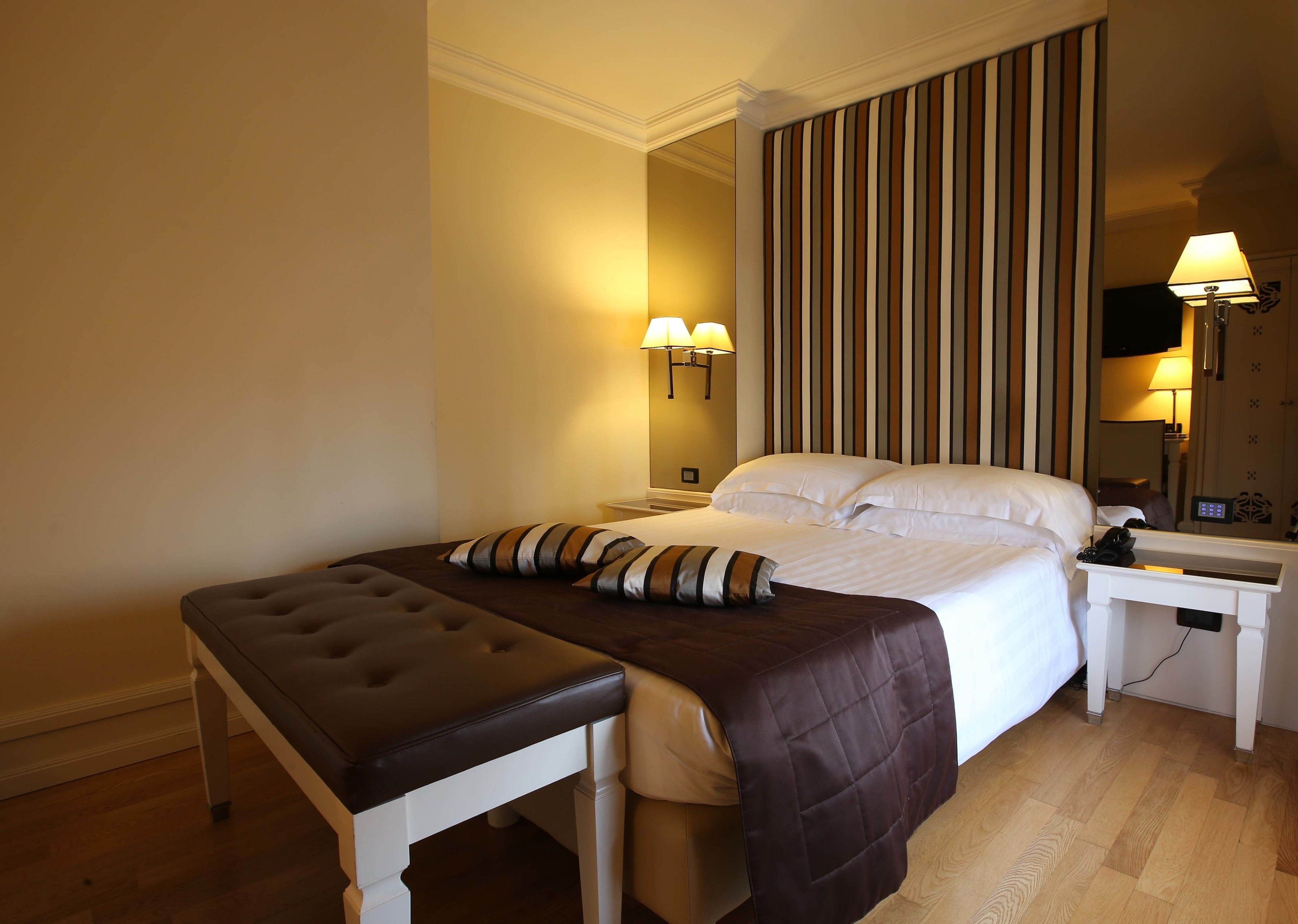 A hotel room with a bed, a bedside table, a lamp, and a TV.