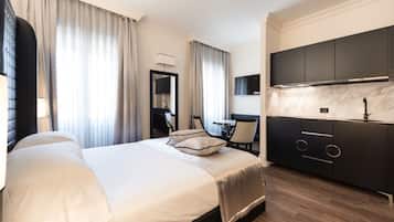 Una habitación de hotel moderna con una cama grande, un espacio de comedor independiente y una cocina.