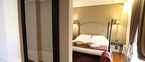 A hotel room with a bed, bedside lamps, a nightstand, and a mirror.
