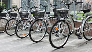 Varias bicicletas con cestas, estacionadas sobre un suelo de baldosas.