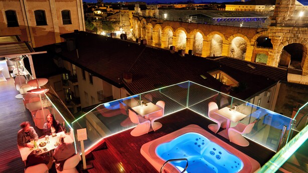 A rooftop terrace with a hot tub, seating area, and a view of historic architecture. - Hotel Milano & Spa (Verona)