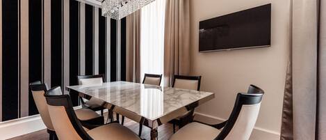 Un comedor moderno con una mesa de mármol, seis sillas, una araña y un cuadro grande en la pared.