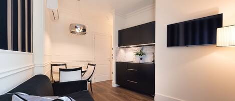 A modern, compact living space with a sofa, dining table, and kitchen area.
