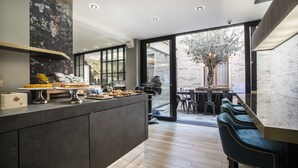 A modern kitchen with a central island, a dining area with a large table and chairs, and a view of the outdoors through large windows. - Hotel Milano & Spa (Verona)