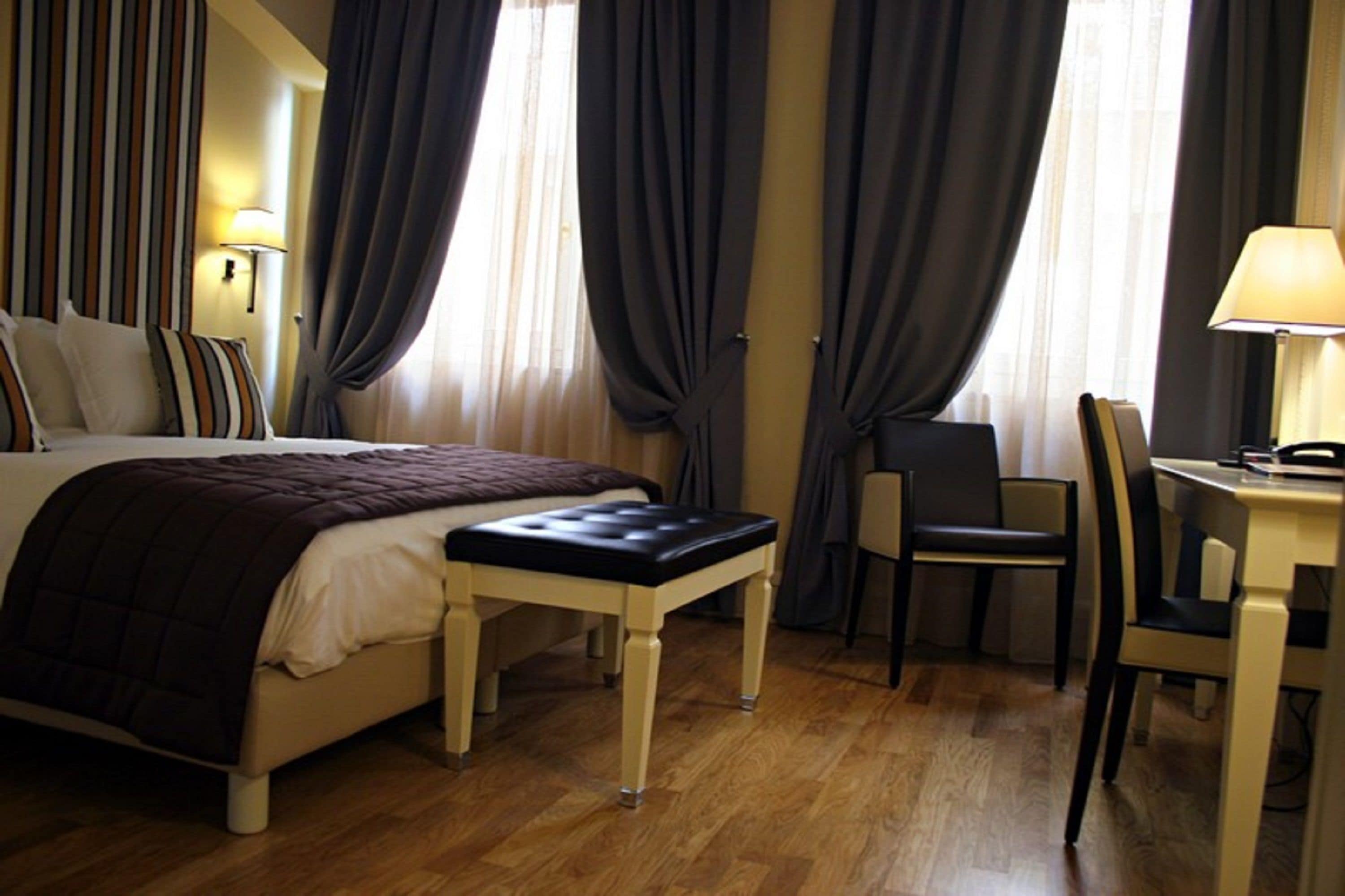 Una habitación de hotel con una cama, un escritorio, una silla y una lámpara.