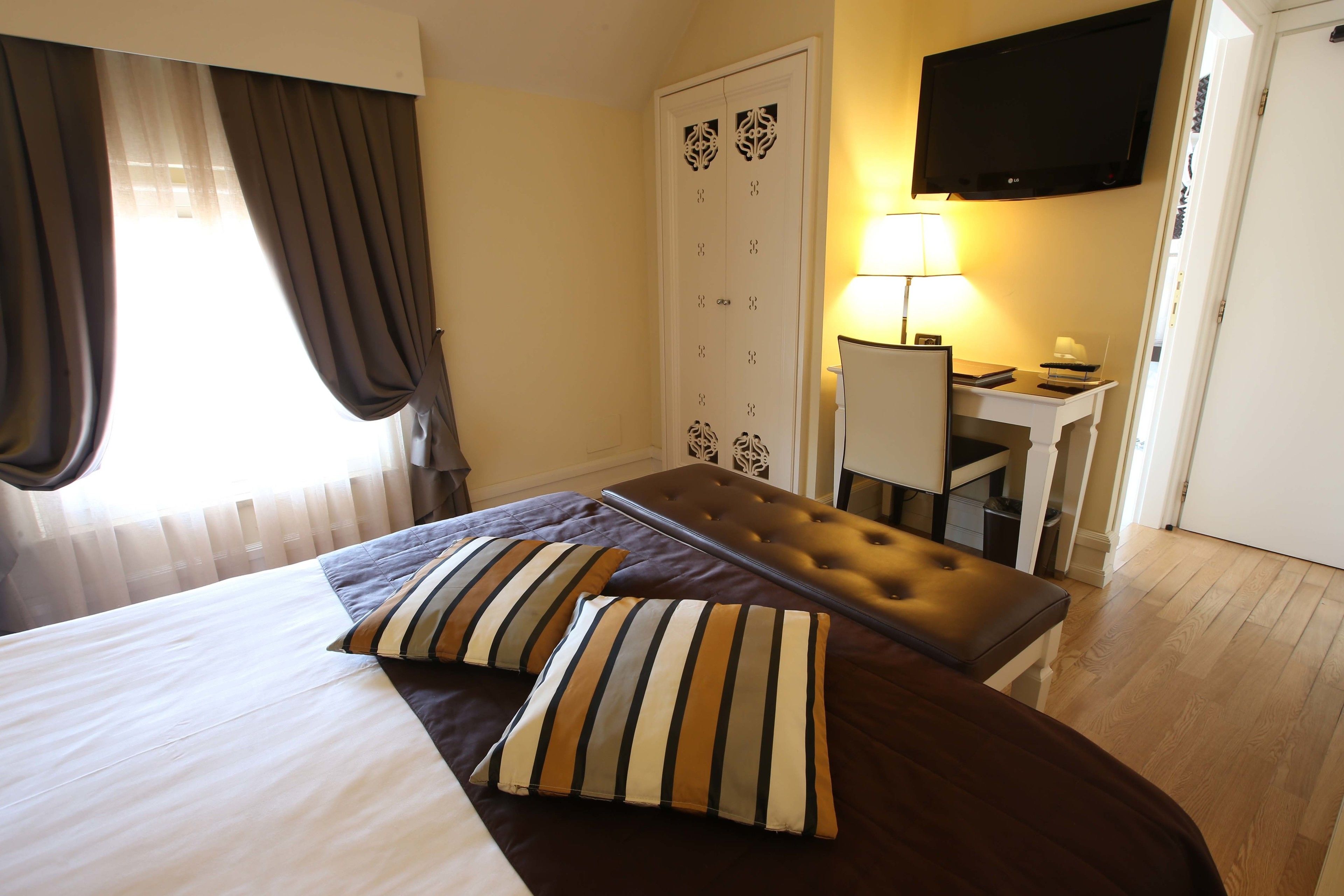 A hotel room with a bed, a desk, a television, and a wardrobe.