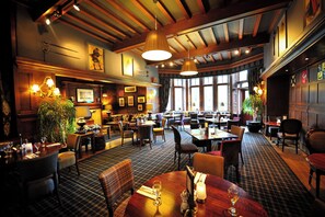 A restaurant with a checkered floor, wooden ceiling beams, and various seating arrangements including tables and chairs. - Savoy Park Hotel (Ayr)
