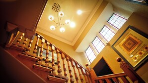 A grand staircase with a wooden balustrade and a chandelier. - Savoy Park Hotel (Ayr)