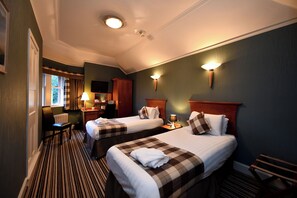 A hotel room with two beds, a desk, a chair, a lamp, and a television. - Savoy Park Hotel (Ayr)