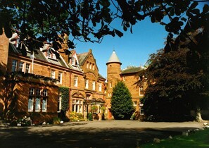 A historic building with a prominent tower, a large central entrance, and a well-maintained garden. - Savoy Park Hotel (Ayr)