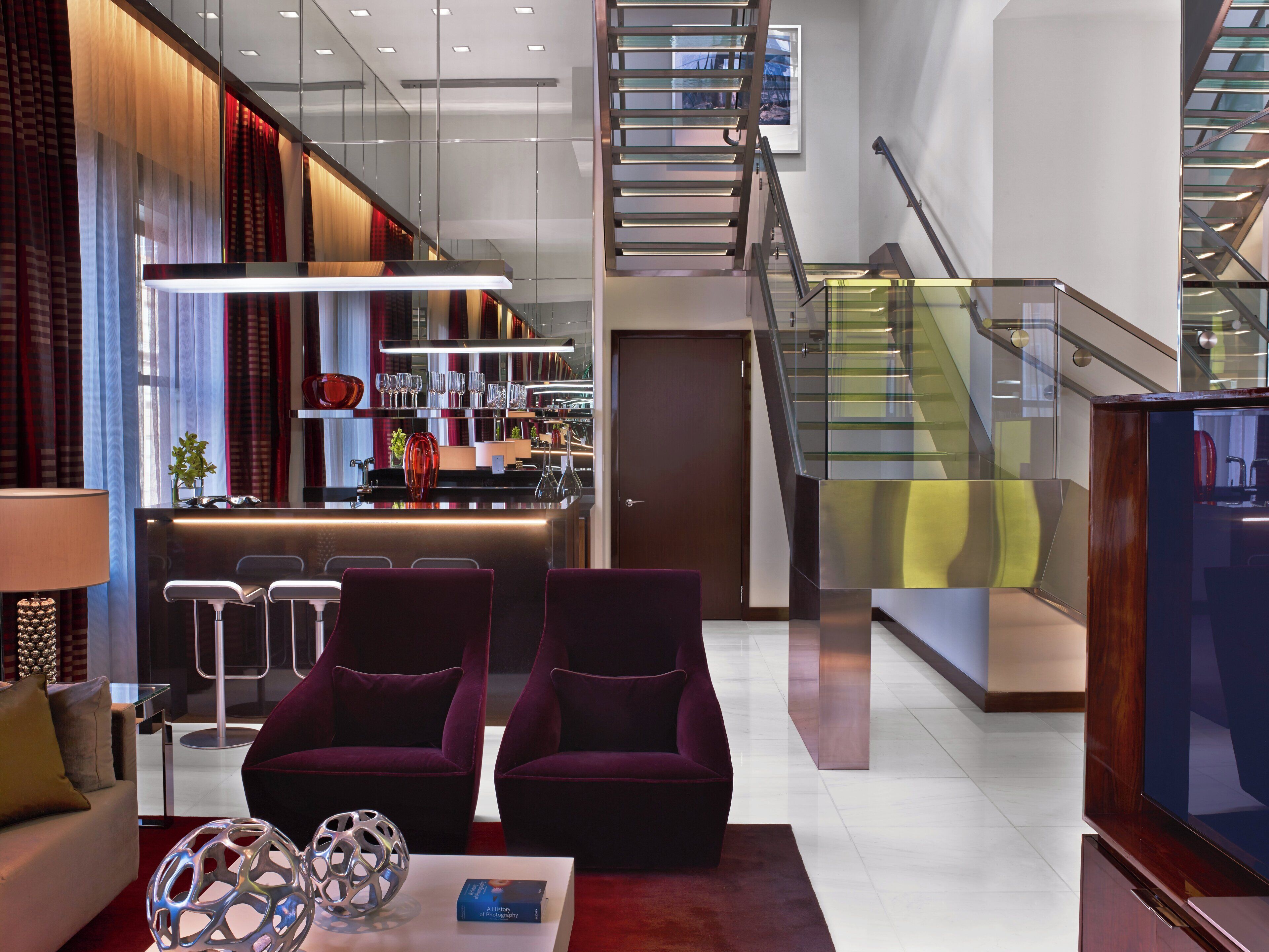 A modern interior with a bar area, seating, and a staircase.