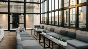 Een modern interieur met een lange grijze bank, zwarte tafels en potplanten.