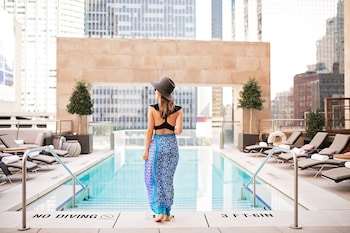 Relax by the rooftop pool with a stunning city view, surrounded by lounge chairs and sunbeds. at The Joule