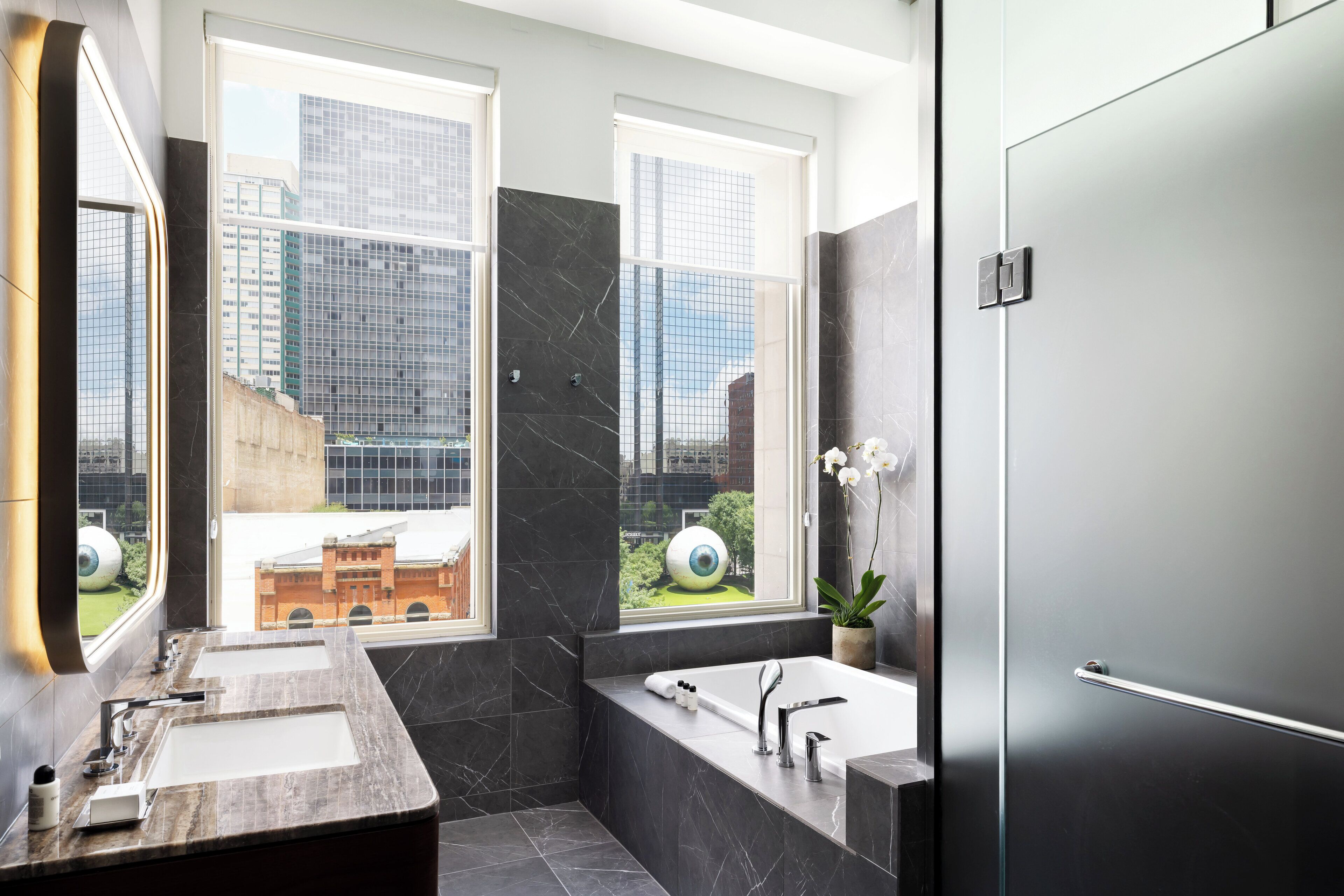 A modern bathroom with two sinks, a bathtub, and a large mirror.