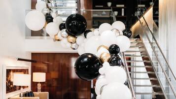 A staircase with a modern design, surrounded by a decorative arrangement of white, black, and gold balloons.