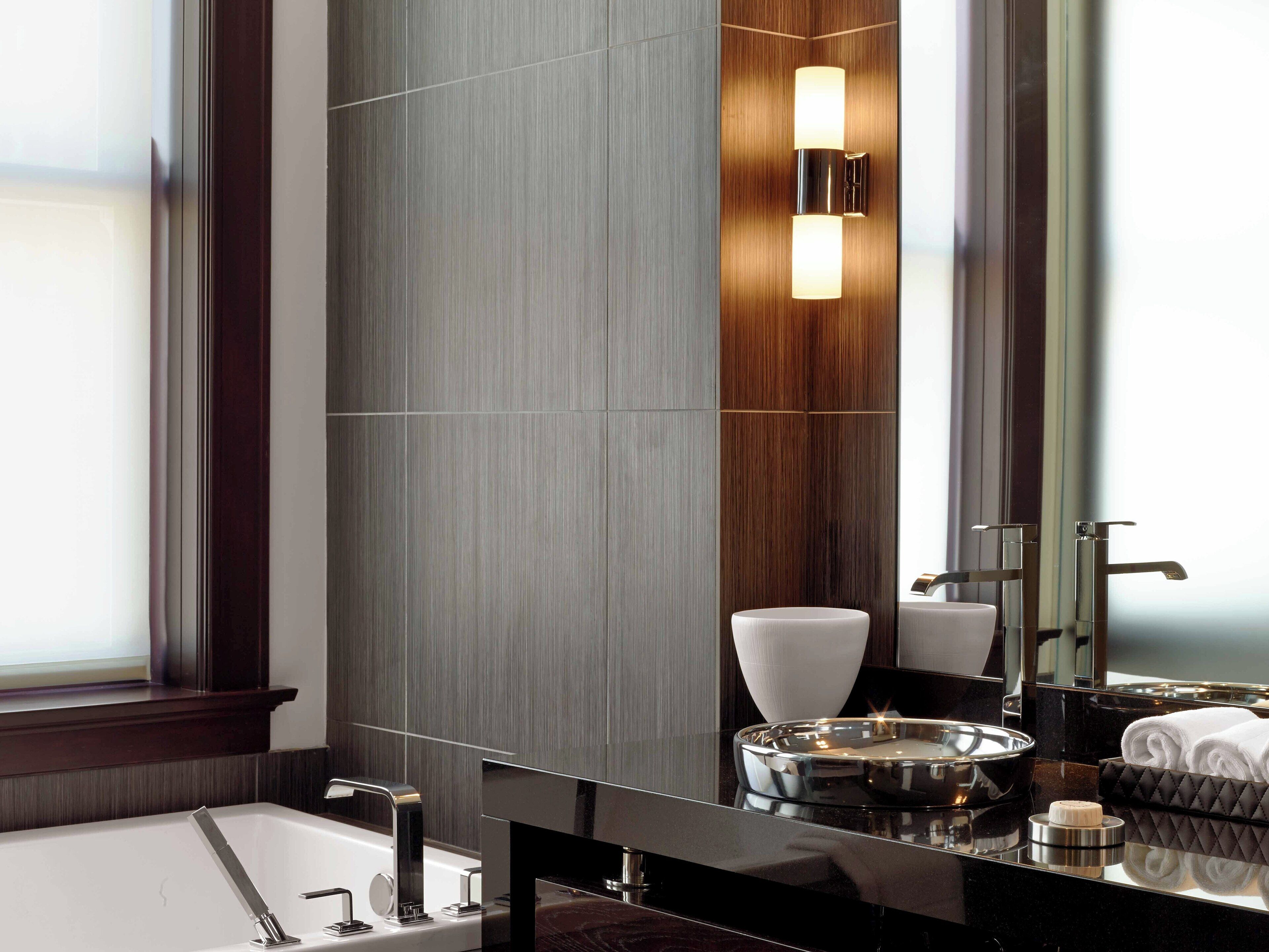 A modern bathroom with a large mirror, a bathtub, and a vanity with a sink.