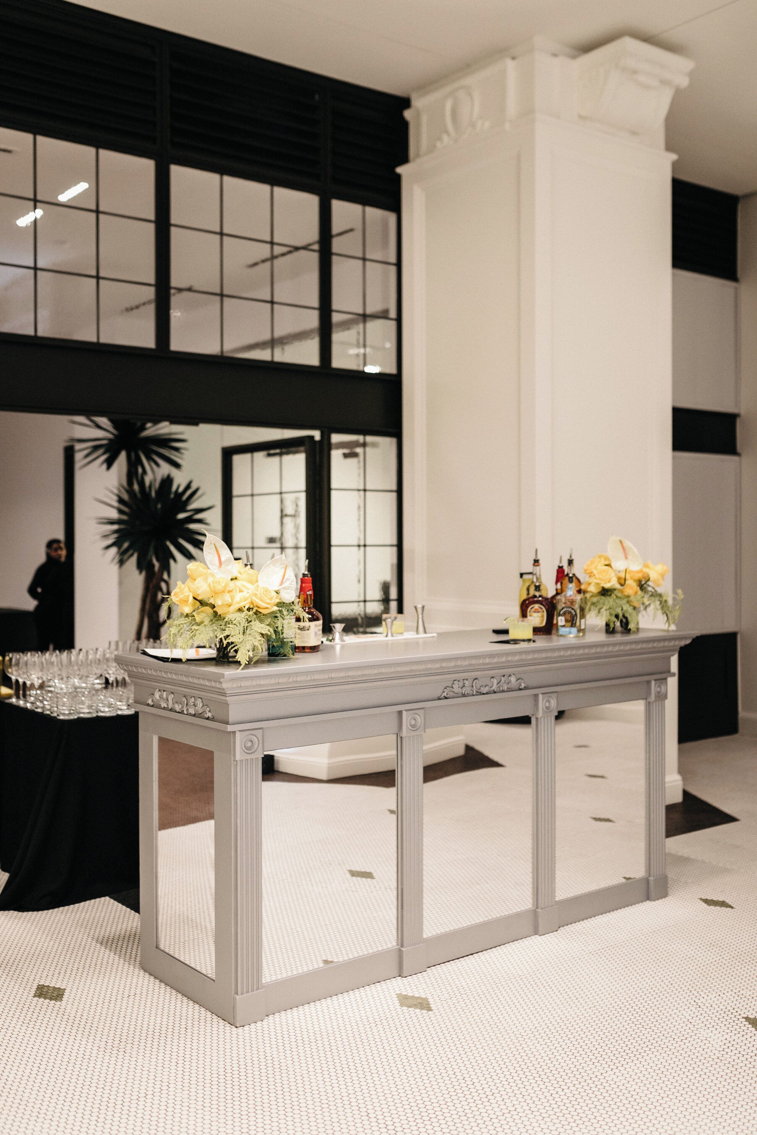 A reception area with a reception desk, a large potted plant, and a window with blinds.