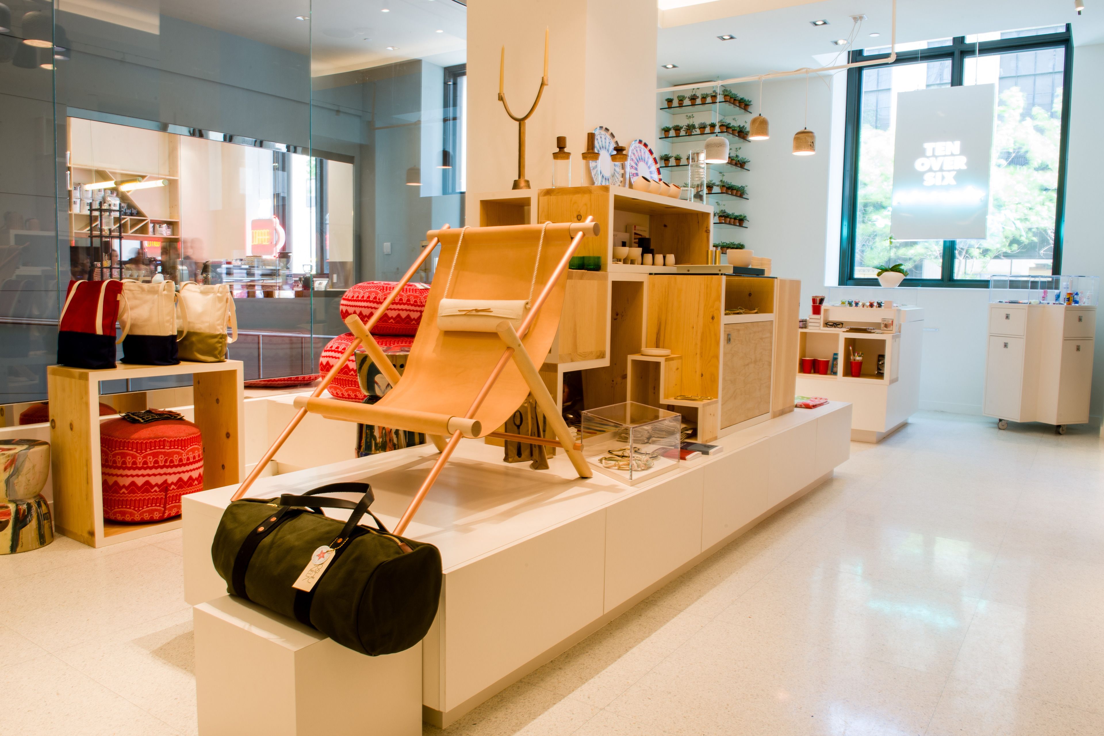Un espacio comercial moderno con estanterías de madera, una silla de madera y varios artículos exhibidos.