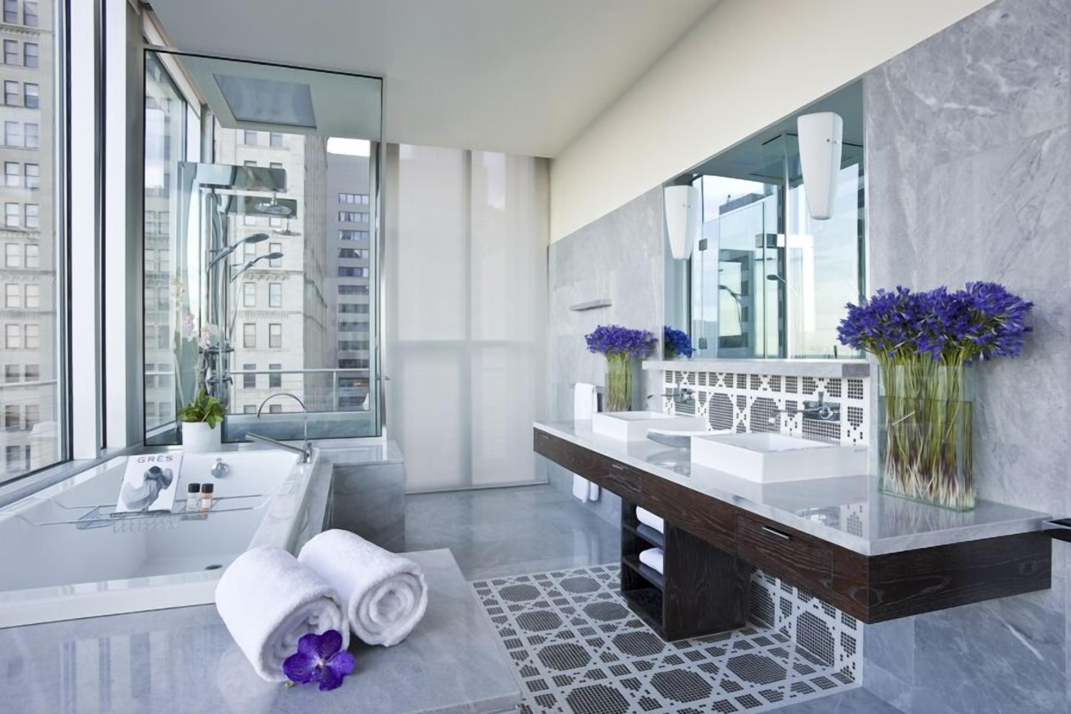 A modern bathroom with a glass-enclosed bathtub, a large mirror, and a vanity with two sinks.