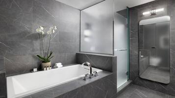 Une salle de bain moderne avec une grande baignoire, une douche en verre et un mur recouvert de carreaux de marbre.