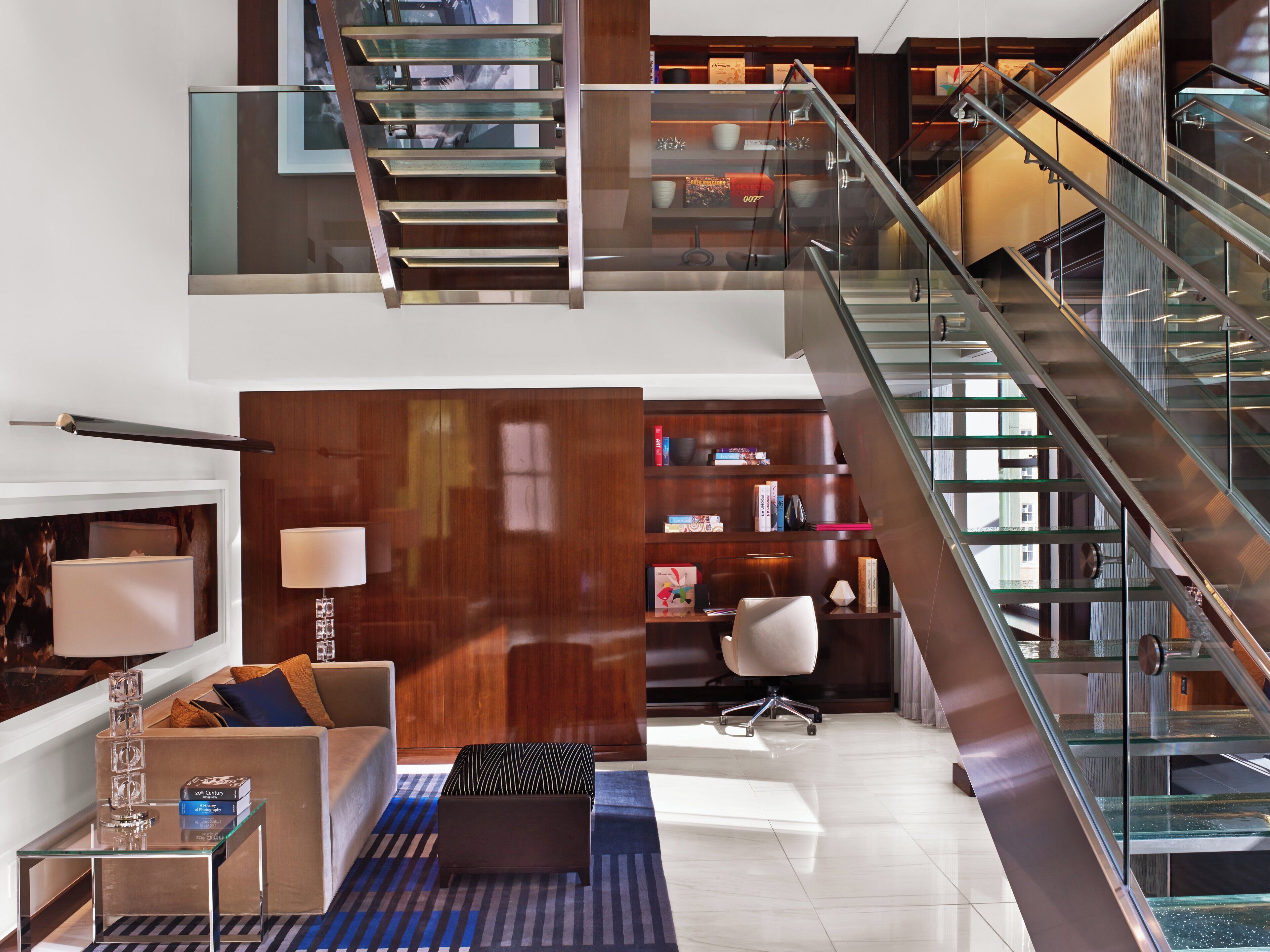 Un intérieur moderne avec un escalier, un canapé, une table basse et une bibliothèque.