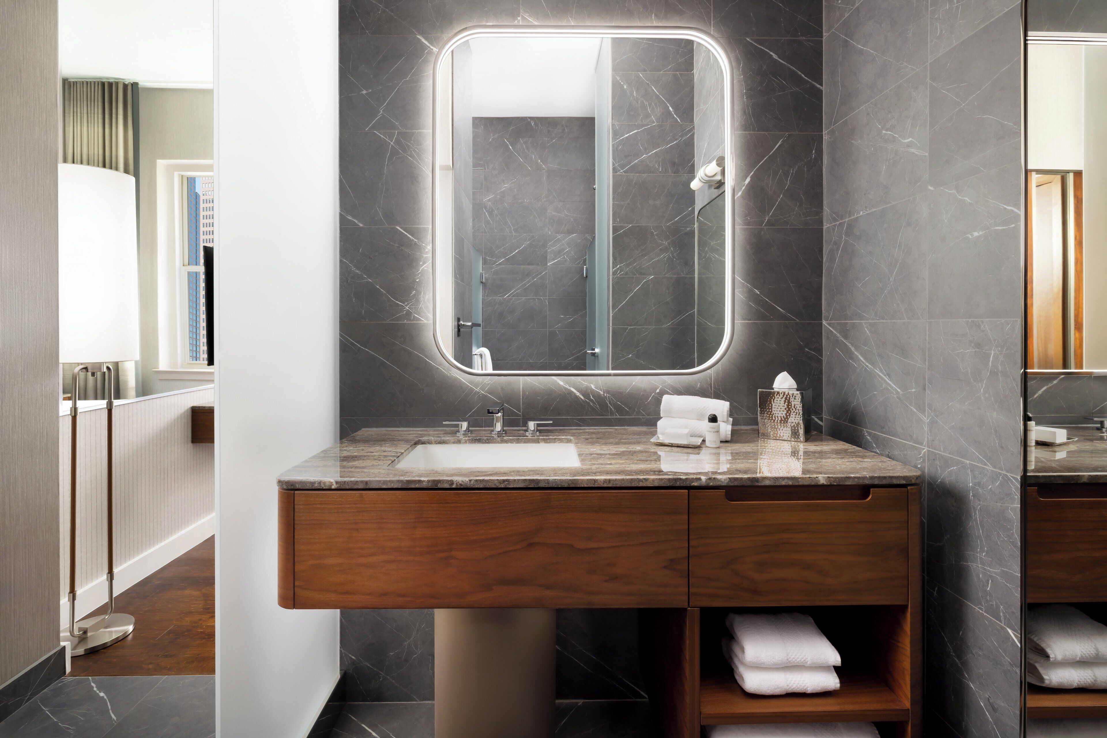 Une salle de bain moderne avec un meuble-lavabo en marbre, un grand miroir et un porte-serviettes.