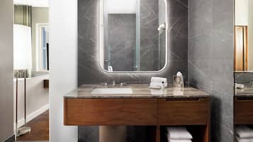 Un baño moderno con tocador de mármol, un espejo grande y un perchero para toallas.