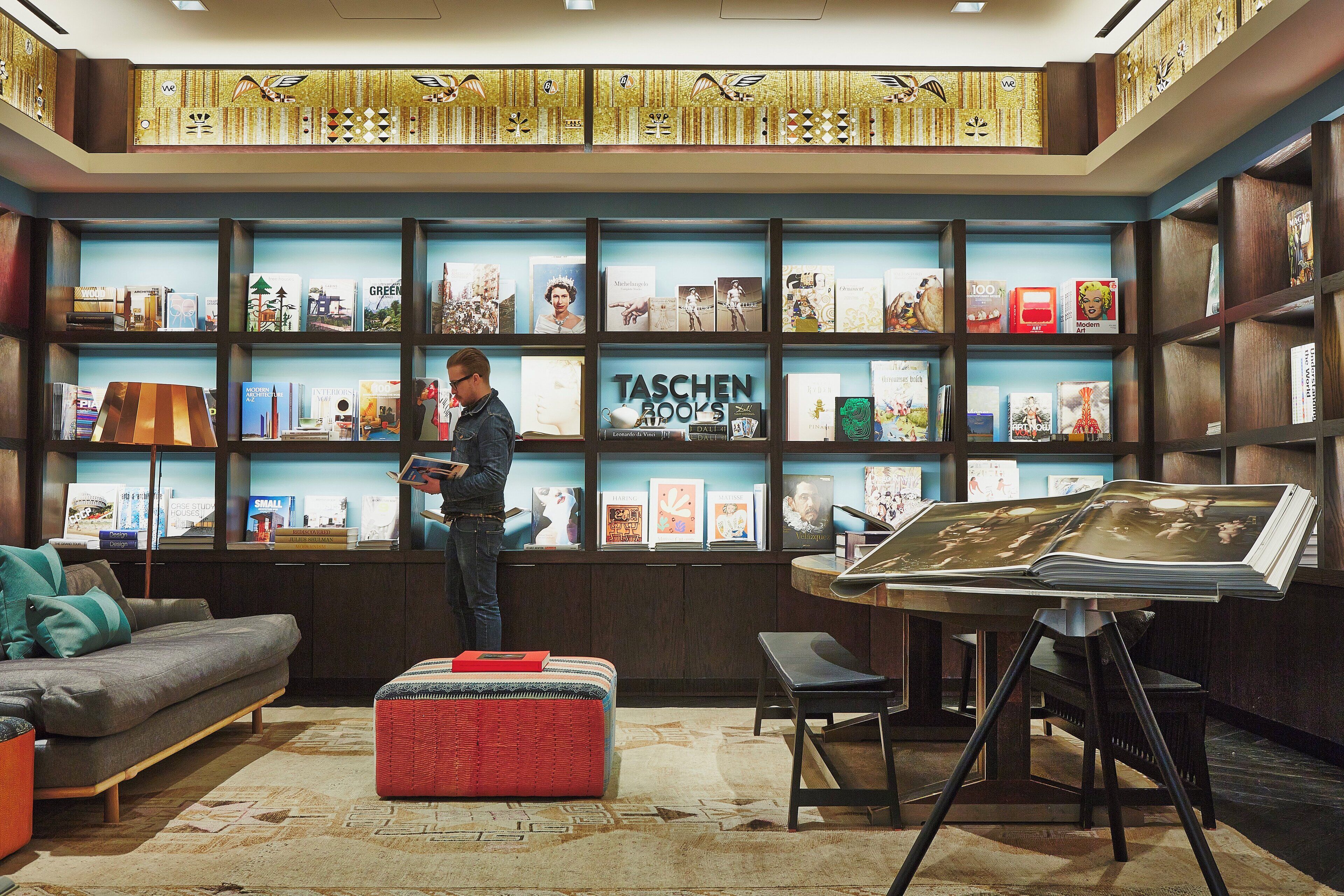 A modern library with bookshelves, a reading area, and a large painting on display.