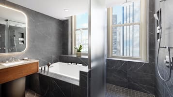A modern bathroom with a large mirror, a bathtub, and a shower area.
