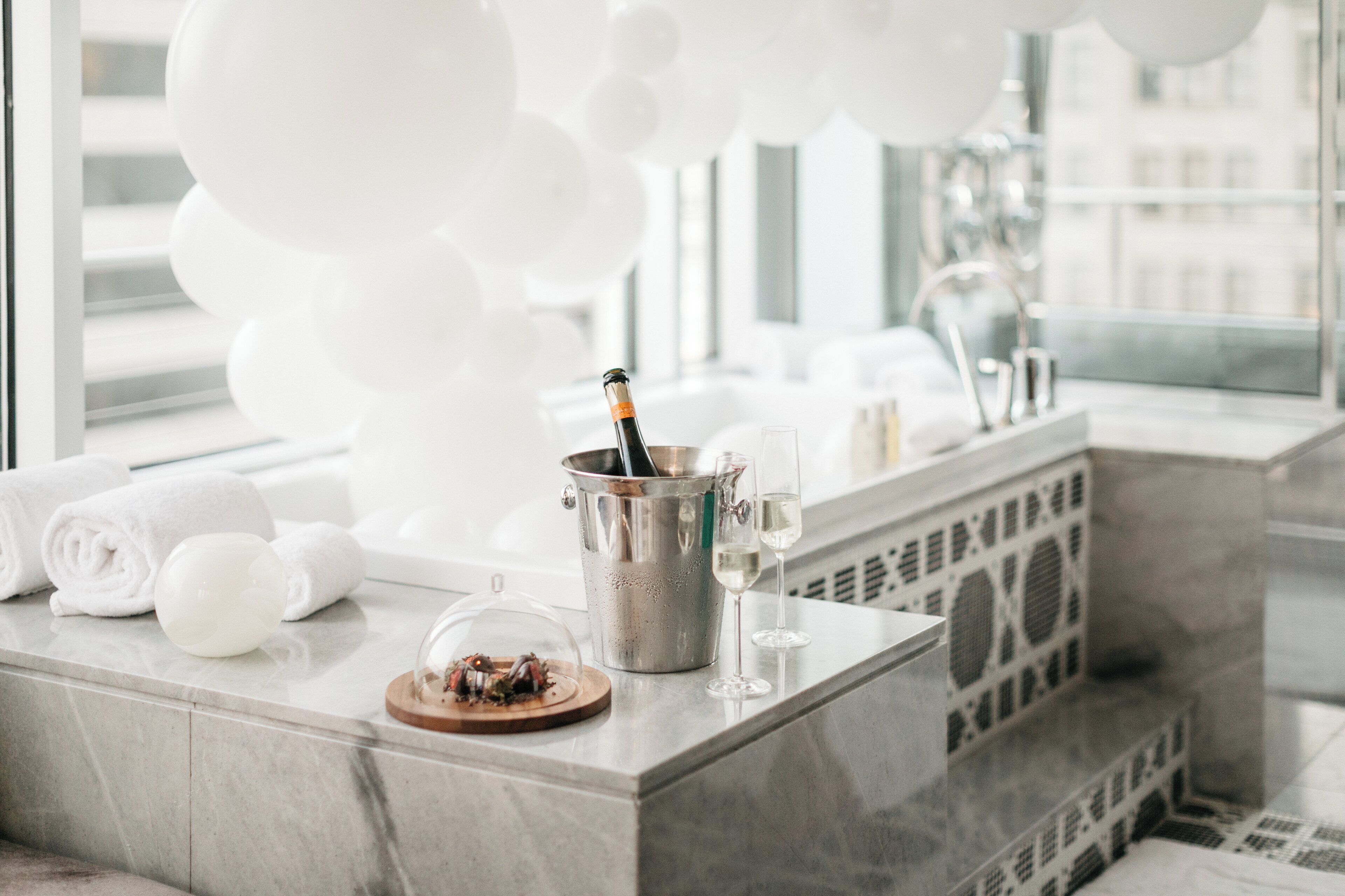 Une salle de bain moderne avec un comptoir en marbre, une bouteille de champagne et un verre de champagne.