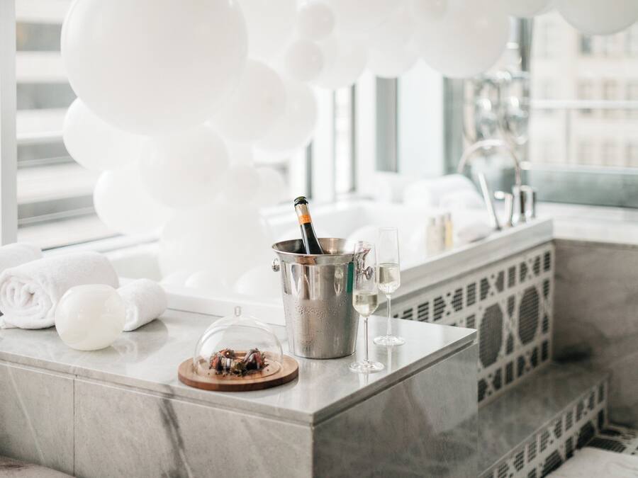 Une salle de bain moderne avec un comptoir en marbre, une bouteille de champagne et un verre de champagne.