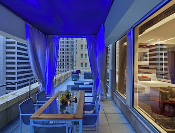 Enjoy the city view from this spacious balcony with a glass table, sofas, and armchairs. at The Joule