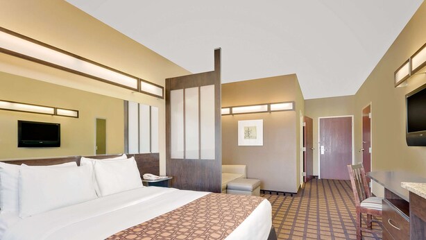 A hotel room with a large bed, a desk, a chair, and a television.