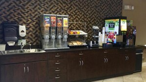 A kitchen area with a dark wood cabinet, a coffee machine, a fruit display, and a refrigerator.