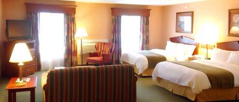 Une chambre d’hôtel avec deux lits, un canapé, une télévision et une lampe.