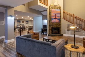 Amplia sala de estar con chimenea, un sofá y un comedor al fondo.