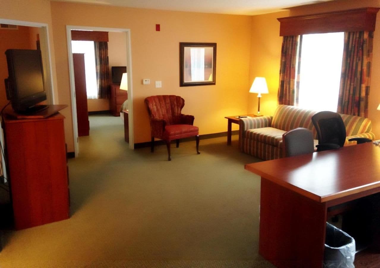 Une chambre d’hôtel équipée d’une télévision, d’un bureau, d’une chaise, d’un canapé et d’une lampe.