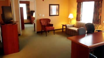 Une chambre d’hôtel équipée d’une télévision, d’un bureau, d’une chaise, d’un canapé et d’une lampe.