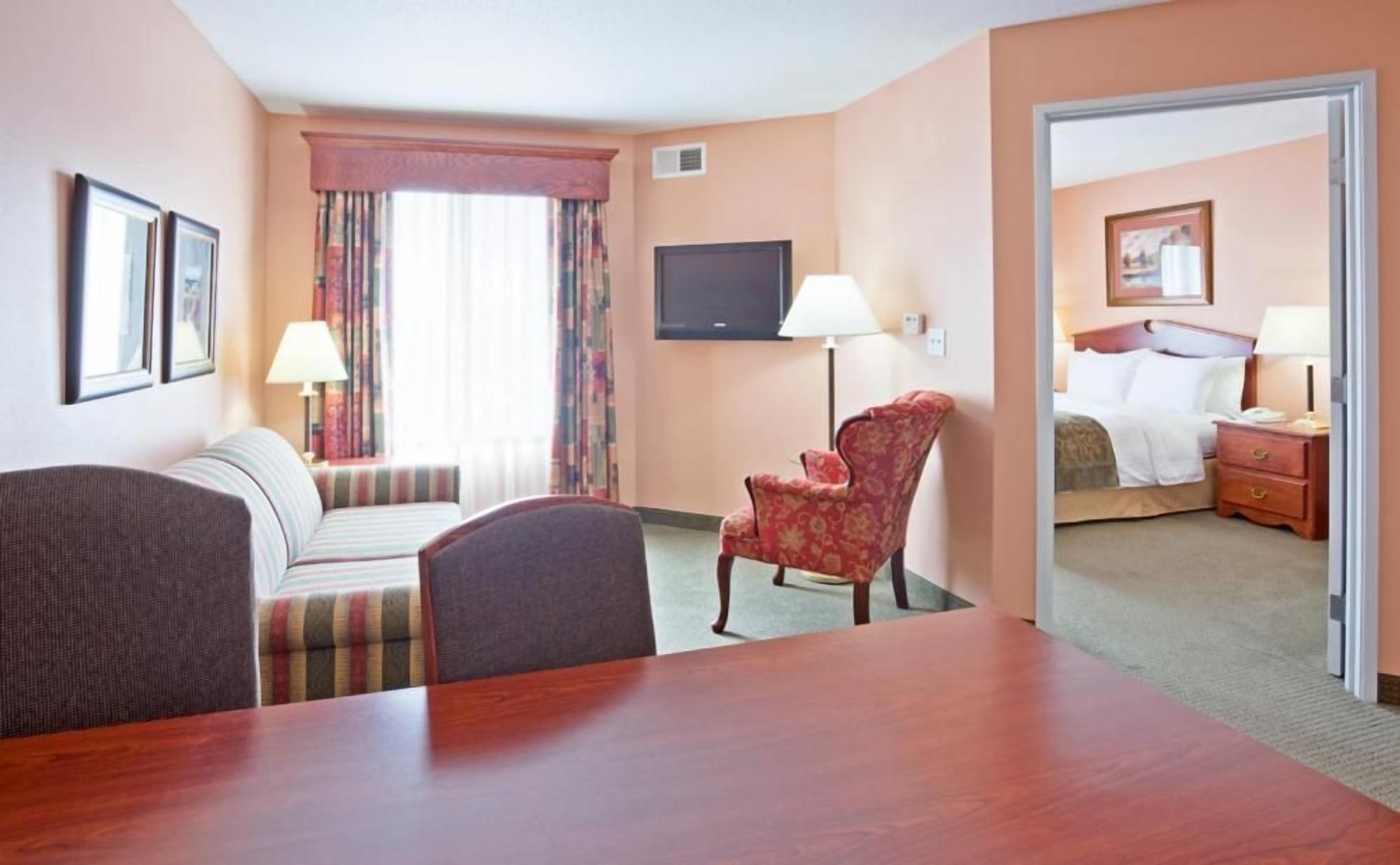 A hotel room with a sofa, a chair, a TV, a bed, and a desk.