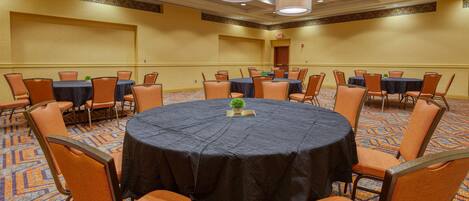 A conference room with a round table, orange chairs, and a carpeted floor.